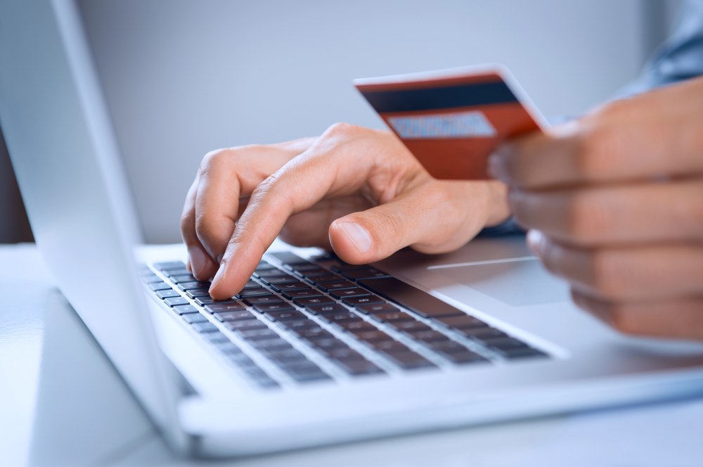 Image of a man making an online payment with a credit card, featuring 411 Corporate Law and highlighting cross-border transactions, ensuring it aligns with the page's context on international business dealings and financial regulations.