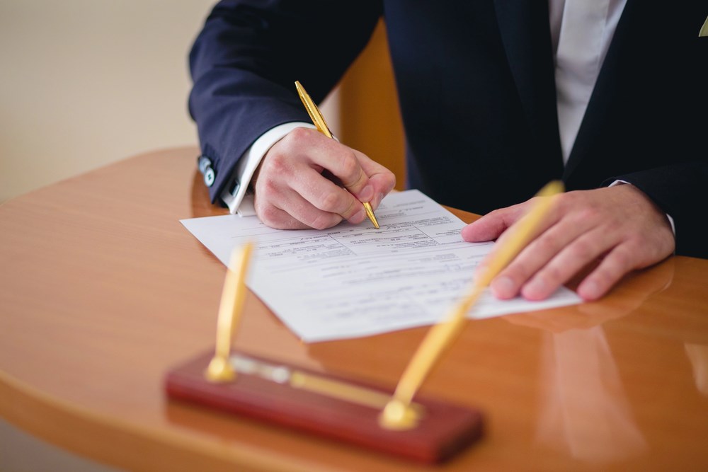 Ensuring Compliance with Corporate Laws Image of a businessman signing a contract, featuring 411 Corporate Law and highlighting the importance of ensuring compliance with corporate laws, aligned with the page's focus on legal corporate governance.